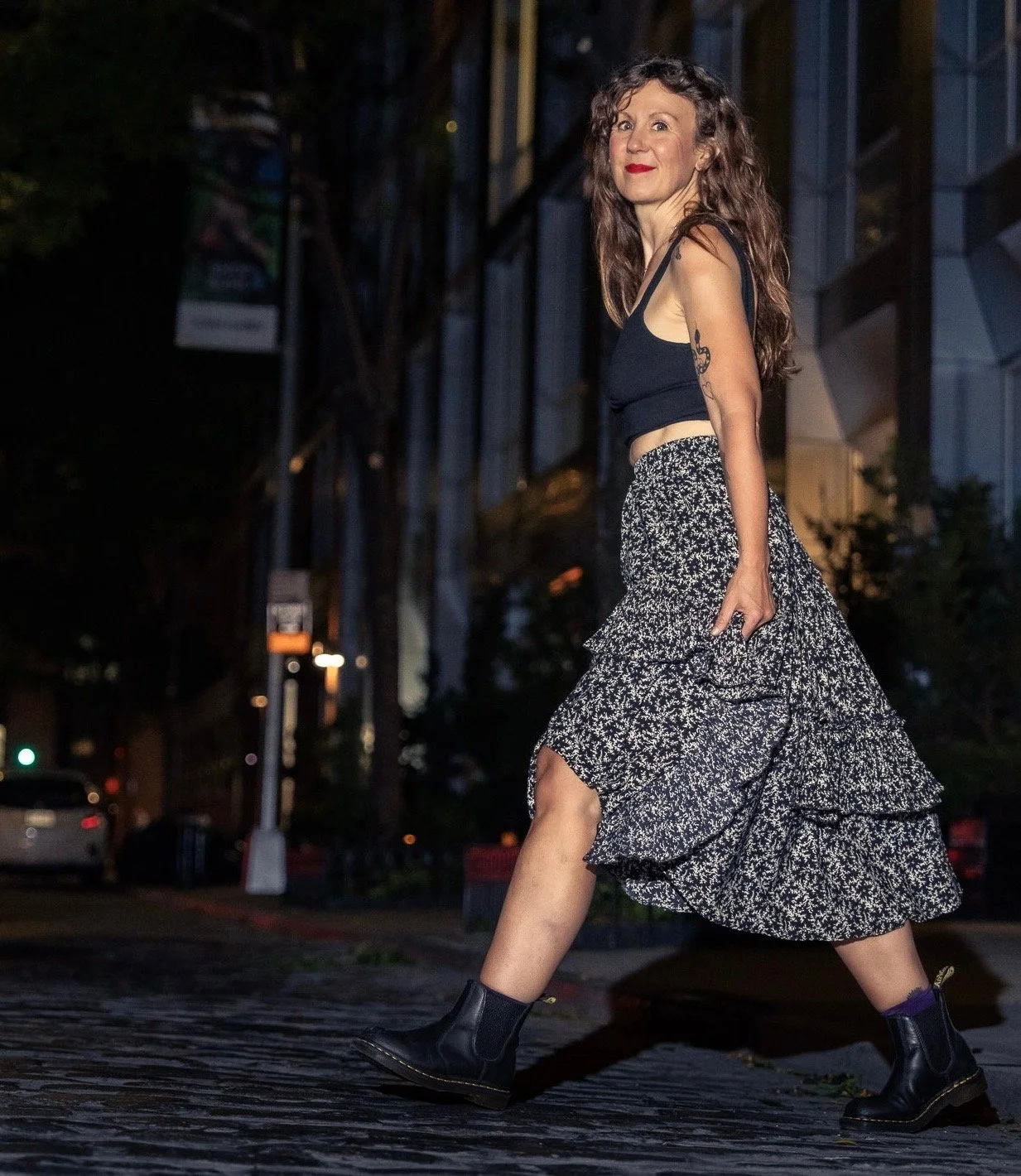 Elizabeth Laura Nelson crossing a cobblestone street in Brooklyn at night